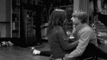 a man and a woman are sitting on the floor hugging and kissing .