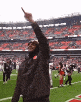 a man wearing a brown jacket with the number 22 on it stands on a football field