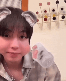 a young woman wearing cat ears and a cat paw making a face .
