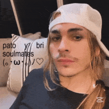 a man with long hair wearing a white hat and a black shirt