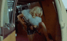 a woman is sitting in the back of a van with a gun .