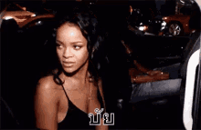 a woman in a black tank top is standing in a car .