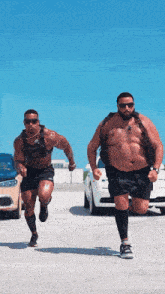 two men are running in a parking lot and one has a weight vest on his back