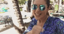 a woman wearing sunglasses and a purple shirt is taking a selfie