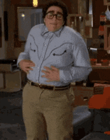 a man wearing a blue shirt and khaki pants is dancing in a kitchen .