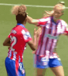 a blurred image of two soccer players with one wearing the number 12