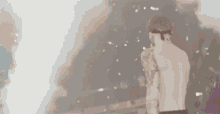 a shirtless man in a baseball cap is standing in front of a cloud of smoke in a dark room .
