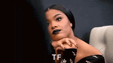 a woman with black lipstick on her lips is sitting in a chair with her hands on her face .