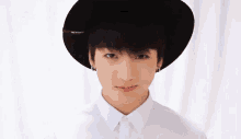 a young boy is wearing a black hat and a white shirt .