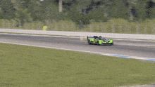 a green race car is driving on a race track