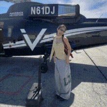 a woman stands in front of a plane with the numbers n61dj on the side