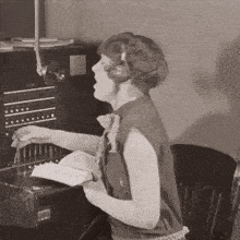 a woman wearing headphones is sitting at a desk with a book in her hand