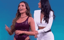 two women standing next to each other on a blue background .