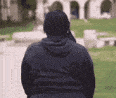 a man in a black hoodie is walking down a path .