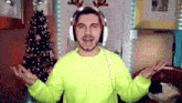 a man wearing headphones and a reindeer antlers headband is standing in front of a christmas tree .