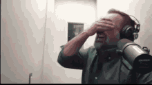 a man wearing headphones is crying in front of a microphone .