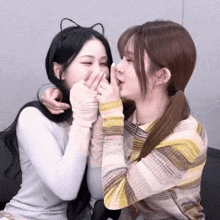 two girls are playing with each other and one has a cat ear headband