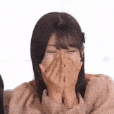 a young woman is covering her mouth with her hands while laughing .