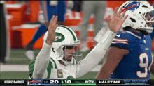 a jets player high fives a buffalo player during a football game