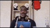 a man wearing headphones and a hoodie is standing in front of a shelf with boxing gloves .