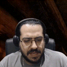 a man with a beard and glasses is wearing headphones .