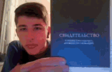 a young man is holding a book that says " свидетельство " on it