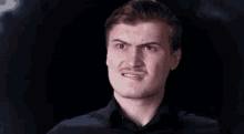 a man with a mustache is making a funny face in a dark room .