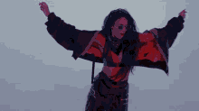 a woman in a crop top and black pants is dancing with her arms outstretched