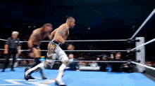 two men are wrestling in a ring and one is wearing a belt with the letter a on it