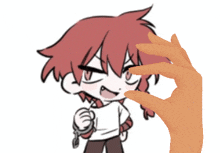 a hand is holding a small object in front of a girl with red hair
