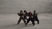 three women are dancing in front of a wall and one of them is wearing a fur coat