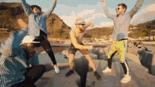 a group of men are dancing with their arms in the air and one of them is wearing a hat