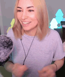 a blonde woman wearing a grey t-shirt and headphones is smiling