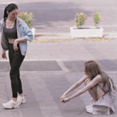 two women are squatting down on the sidewalk with a watermark that says lingoempire