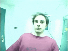 a man in a red shirt is standing in a hallway with a no smoking sign on the door