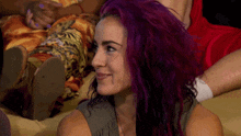 a woman with purple hair is smiling while sitting on a couch ..