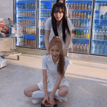 a girl sitting on another girl 's lap in front of a fridge that has a can of sprite on it