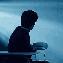 a person is sitting at a desk in a dark room with a chair in front of them .