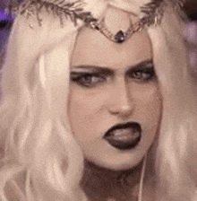 a woman with blonde hair and a crown on her head is making a funny face .