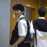 a man wearing a white shirt and a black backpack is standing next to another man