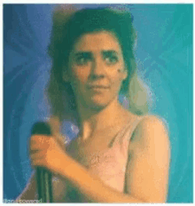 a woman singing into a microphone with a blue background