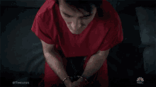 a man in a red scrub is sitting in a dark room with his eyes closed