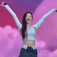 a woman is standing on a stage with her arms outstretched and a microphone in her hand .