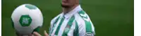 a man in a green and white jersey is holding a soccer ball ..