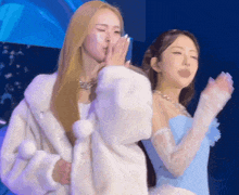 two women are standing next to each other and one is wearing a fur coat