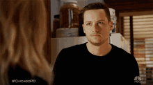 a man in a black shirt is looking at a woman with #chicagopd written on the bottom of the screen
