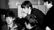 a group of young men are smoking cigarettes in a black and white photo .