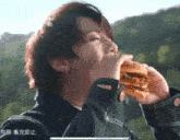 a person eating a hamburger with chinese writing on the bottom