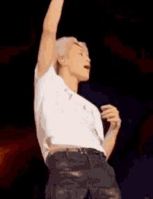 a man in a white shirt is dancing on a stage with his arm in the air .