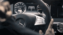 a person is driving a mercedes with a steering wheel and a dashboard .